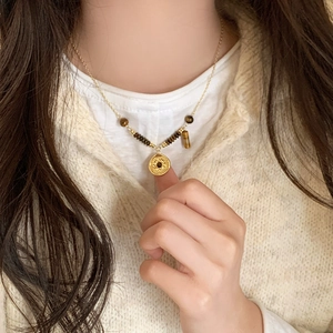 Retro tiger eye stone beaded necklace with a gold coin pendant worn by a model