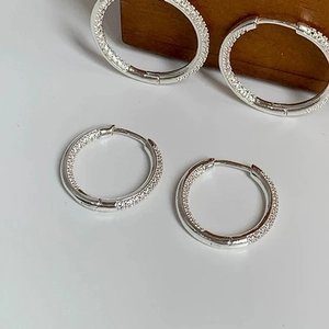 Macro detail of silver pavé hoop earrings featuring micro-set cubic zirconia crystals