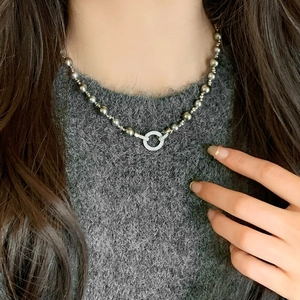 French vintage grey pearl necklace with zircon pavé pendant on grey knitwear backdrop
