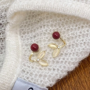 Elegant gold fishtail earrings with red pearls and cat eye stone on white knit