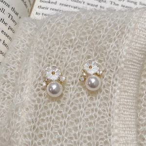 Detailed close-up of pearl flower earrings with crystals on a soft knit background