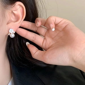 Close-up of shell flower earrings with small zircon accents and round pearl drops
