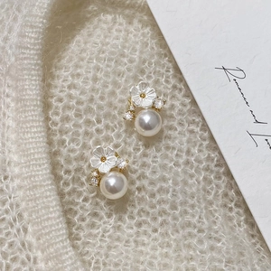 Elegant gold shell flower earrings with white pearls and crystals on soft knit fabric