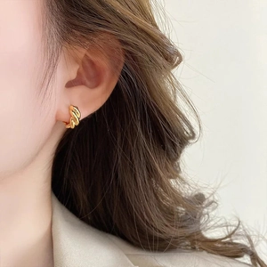 Boucles d'oreilles créoles torsadées dorées 18 carats portées par un mannequin