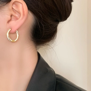 Elegant gold plated spiral hoop earrings with white enamel worn by a fashion model