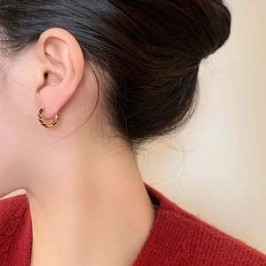 Eleganti orecchini a cerchio dorati con smalto rosso a spirale indossati da modella