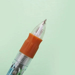 Macro detail of multi-color ballpoint pen with orange rubber grip and clear barrel