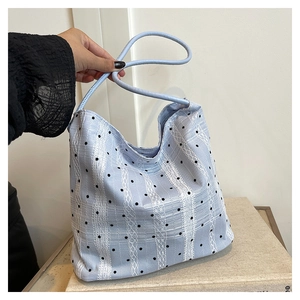 Detail of light blue plaid bucket bag with white lace stripes and black polka dots