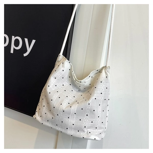 Detail of white checkered bucket bag with delicate lace embroidery and thin rope straps