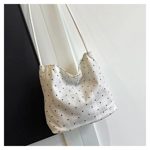 Detail of off-white lace bucket bag with black polka dots and fine crochet texture