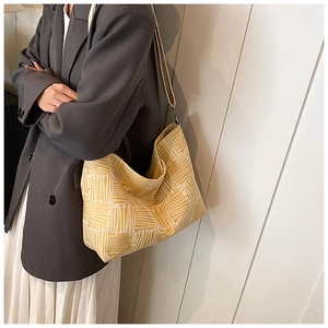 Detailed view of yellow geometric canvas tote bag styled with a gray suit and white dress