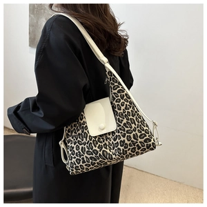 Détail du sac cabas léopard avec rabat en cuir blanc porté sur un manteau noir
