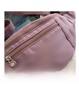 Détail d'un sac banane en nylon à double zip avec logo sport sur fond en jean bleu