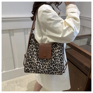Detail of leopard print tote bag with brown leather flap and shoulder strap on model