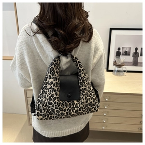 Detail of leopard print tote bag with black leather flap and silver metal ring straps