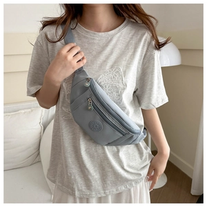 Détail du sac banane en nylon gris avec compartiments zippés et logo de sport
