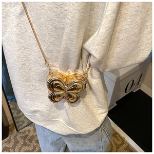Detailed view of butterfly-shaped gold metal mini bag with sleek mirror finish and chain