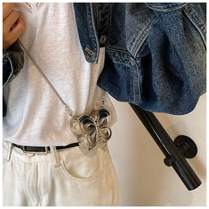 Détail du mini sac papillon argenté avec bandoulière chaîne sur veste en jean