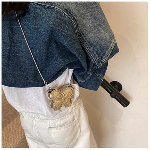 Fashionable golden butterfly hard shell mini bag with silver chain strap worn by a model