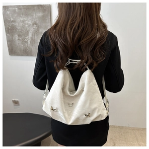Détail du sac hobo crème avec boucles papillon argentées et texture plissée sur la bandoulière