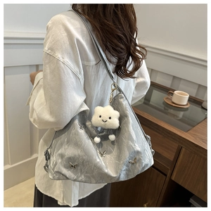 Détail du sac cabas argenté froissé avec boucle papillon et pendentif nuage en peluche
