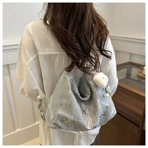 Détail du sac argenté métallisé avec breloques papillons et accessoire ours peluche