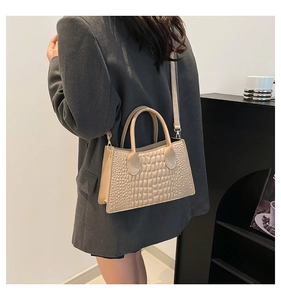 Detailansicht einer beigen PU-Handtasche mit Krokodilmuster und goldenen Metallelementen
