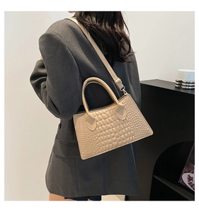 Detailansicht einer beige Handtasche mit Krokodilmuster kombiniert mit einem grauen Blazer