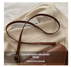 Detail of adjustable brown leather strap with gold metal buckle on shoulder bag
