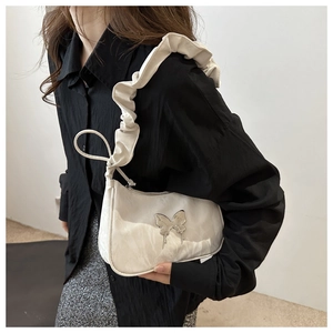 Detail of white crescent shoulder bag with silver butterfly and ruffled strap