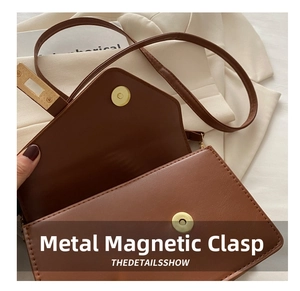 Detailed view of dual magnetic snap closures on the brown leather crossbody bag