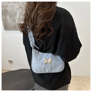 Detail of light blue pleated shoulder bag featuring a metallic silver butterfly buckle