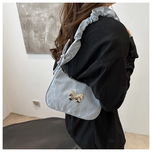 Detail of light blue pleated shoulder bag featuring a metallic butterfly clasp on strap