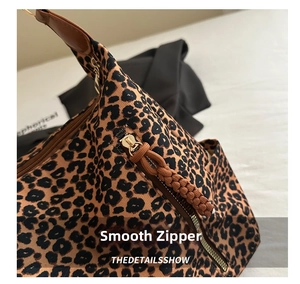 Detail of golden zipper and woven leather puller on leopard print tote bag