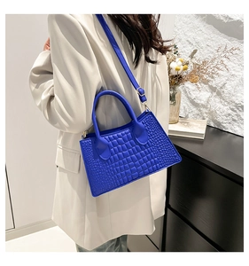 Detail der blauen Handtasche mit Krokodilleder-Struktur und Schultergurt-Design