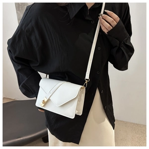 Detail view of white PU leather crossbody bag with rectangle gold clasp and fine stitching