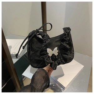 Close-up of black pleated bag featuring silver metal butterfly and glossy crinkled texture