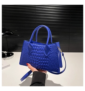 Detailansicht der königsblauen Handtasche mit Krokodilprägung und Goldbeschlägen
