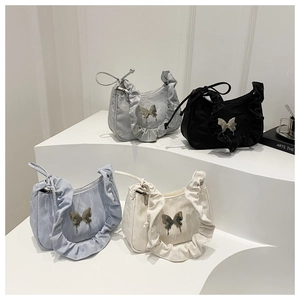 Pleated shoulder bag with metallic butterfly buckle in four colors on minimalist white steps