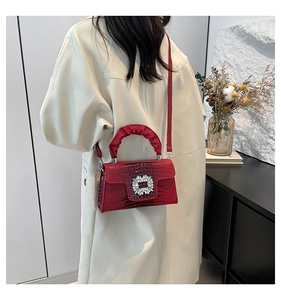 Detail of red crocodile texture handbag with diamond buckle and ruched handle