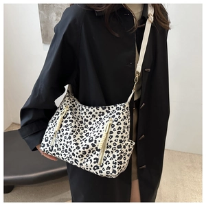 Detail of leopard print crossbody bag with white woven strap and gold metal buckles