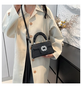 Detail of black crocodile texture handbag with crystal buckle and scrunchie handle