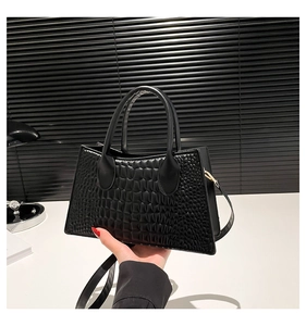 Detail der schwarzen Handtasche mit Krokodilprägung und goldenen Metallelementen