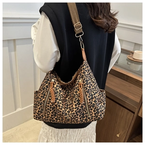 Detail of leopard print tote bag featuring a side metal zipper and adjustable brown strap