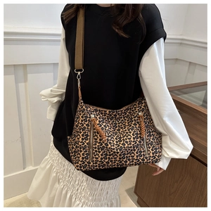 Detail of leopard print tote bag with decorative zippers and a wide brown strap