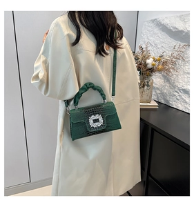 Detail of green crocodile texture handbag with sparkling crystal buckle and pleated handle