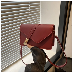 Detail of burgundy matte leather crossbody bag with gold twist lock held by person