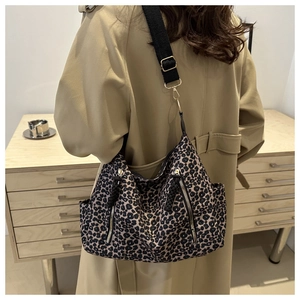 Detail of leopard print tote bag with wide black strap and side zipper accents