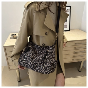 Detail view of leopard print canvas tote bag with functional zippers and black nylon strap