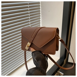 Close-up of brown vintage crossbody bag with golden metal twist lock and leather strap